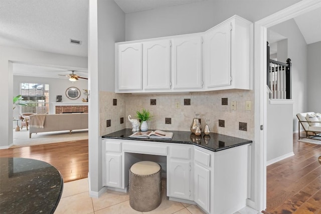 kitchen featuring dark stone countertops, white cabinets, and ceiling fan