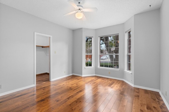 empty room featuring baseboards, a textured ceiling, ceiling fan, and hardwood / wood-style flooring