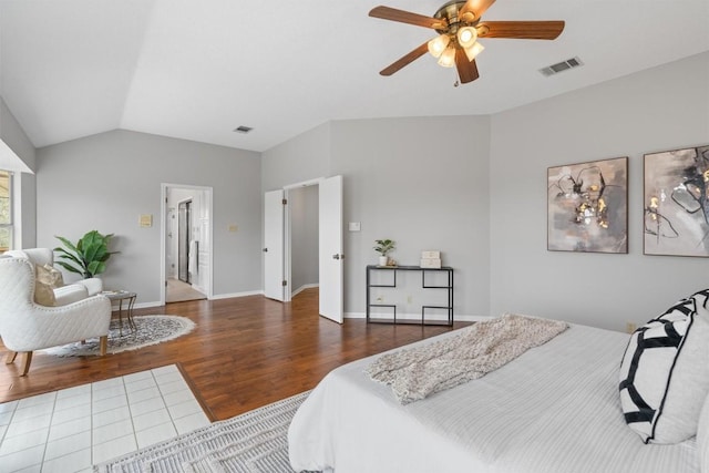 bedroom featuring a ceiling fan, wood finished floors, visible vents, baseboards, and vaulted ceiling