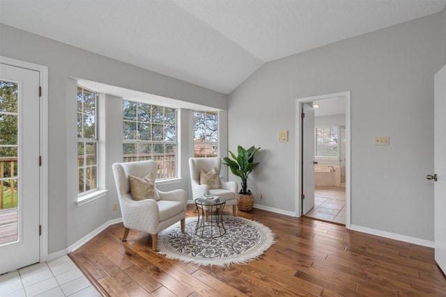 sitting room with baseboards, lofted ceiling, and wood finished floors