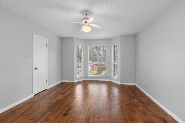 unfurnished room featuring ceiling fan, baseboards, a textured ceiling, and dark wood finished floors