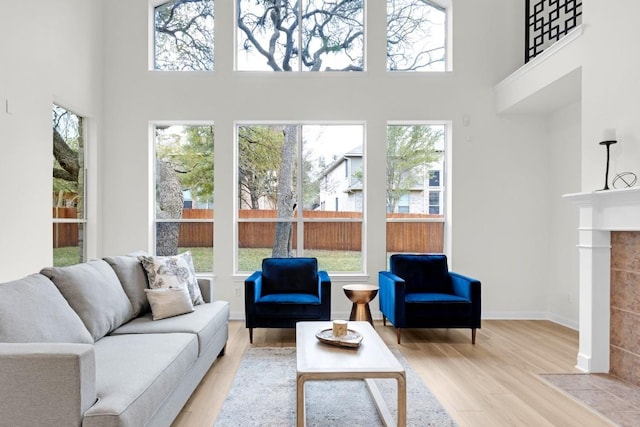 living room with a fireplace, a high ceiling, wood finished floors, and baseboards