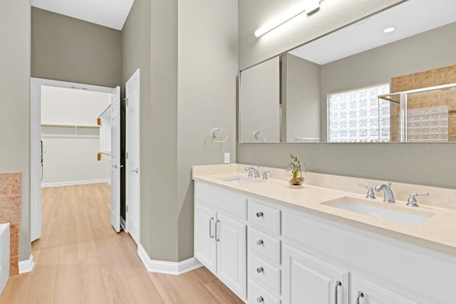 6717 Blissfield Dr, Austin, TX 78739 - full bath with double vanity, wood finished floors, a walk in closet, tiled shower, and a bathtub