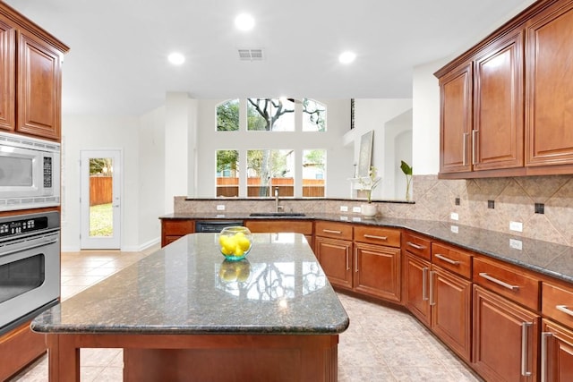 kitchen with white microwave, visible vents, tasteful backsplash, stainless steel oven, and dark stone countertops