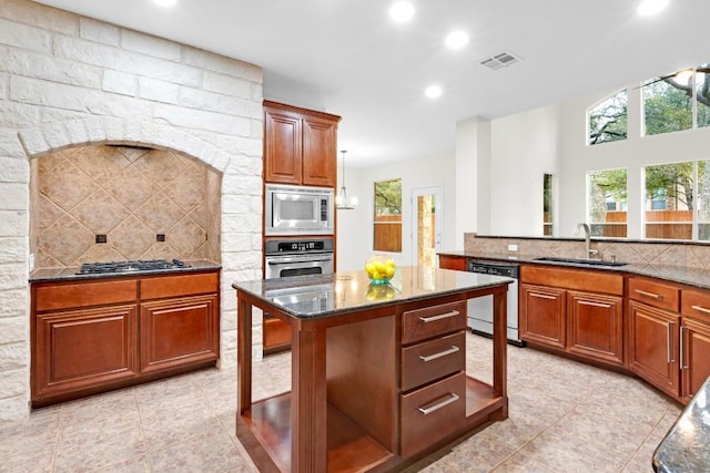 kitchen featuring tasteful backsplash, dark stone countertops, stainless steel appliances, and a sink