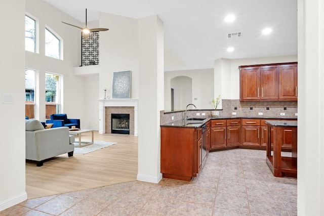 6717 Blissfield Dr, Austin, TX 78739 - kitchen featuring arched walkways, light tile patterned floors, a fireplace, dark stone countertops, and backsplash