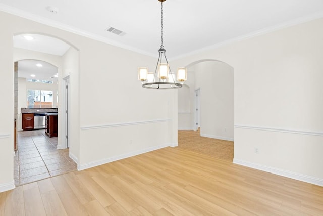 unfurnished dining area with arched walkways, visible vents, crown molding, and light wood-style floors