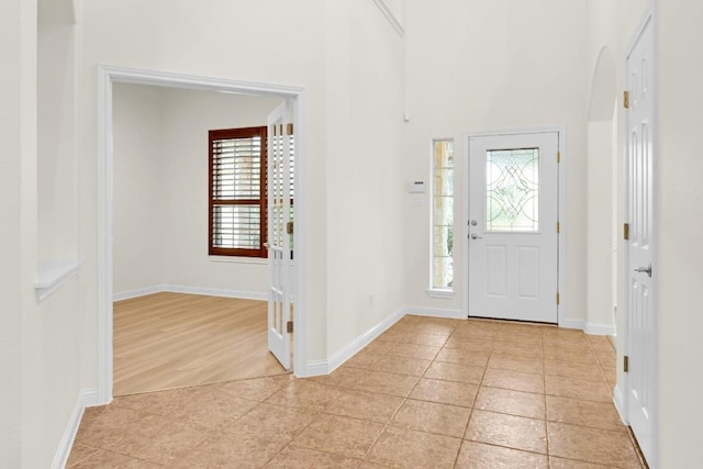 foyer with plenty of natural light, light tile patterned flooring, and baseboards