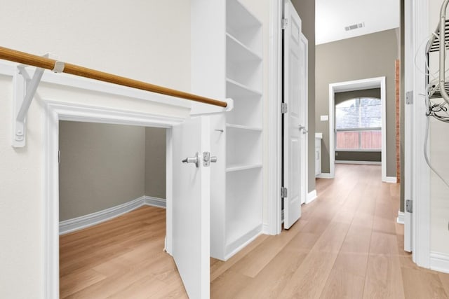 corridor featuring light wood finished floors, visible vents, and baseboards