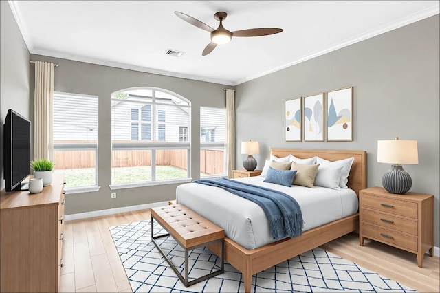 bedroom with visible vents, baseboards, ornamental molding, light wood-style flooring, and a ceiling fan