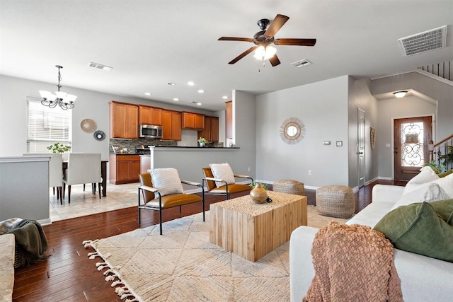 living room featuring visible vents, light wood-style flooring, and ceiling fan with notable chandelier