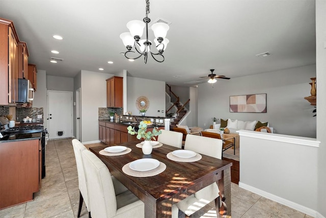 dining space featuring visible vents, ceiling fan with notable chandelier, stairway, light tile patterned flooring, and baseboards