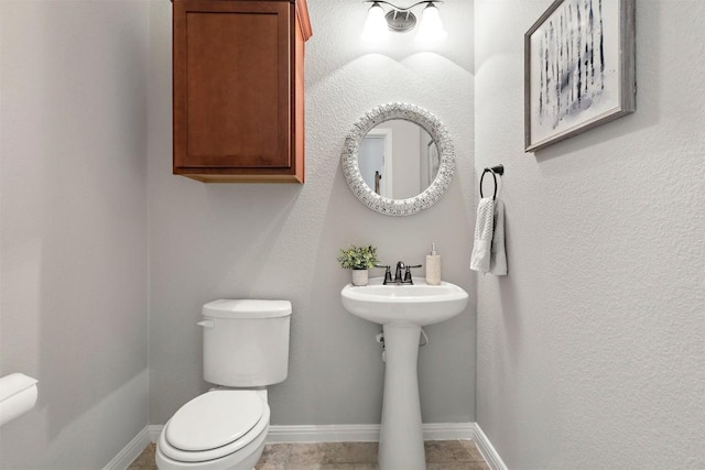 bathroom with tile patterned flooring, toilet, baseboards, and a sink