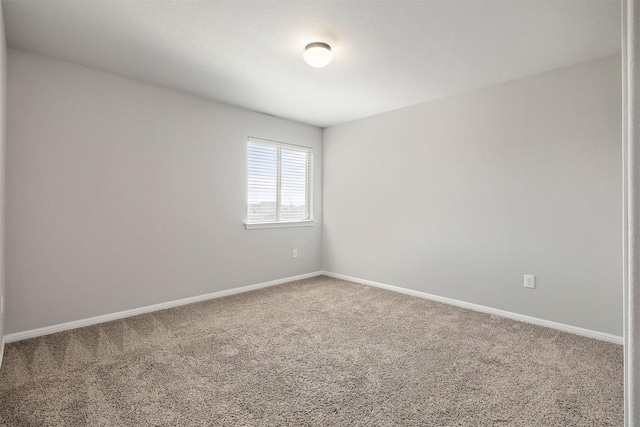 spare room featuring carpet flooring and baseboards