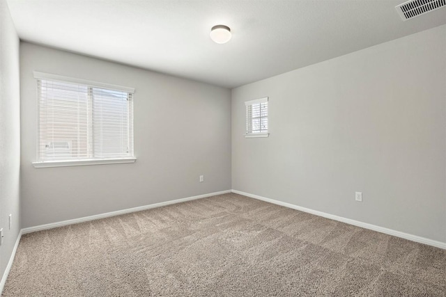 empty room featuring visible vents, baseboards, and carpet