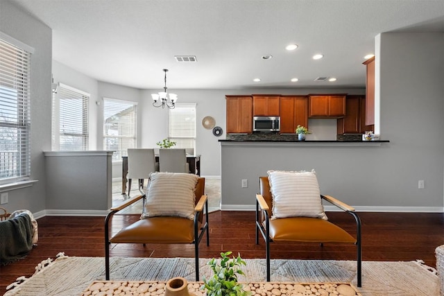 living area with dark wood finished floors, a notable chandelier, baseboards, and visible vents