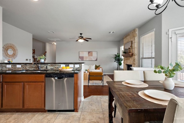 kitchen with dishwasher, brown cabinets, a fireplace, a ceiling fan, and a sink