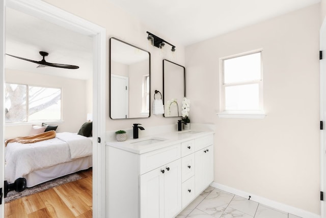 full bathroom featuring marble finish floor, ensuite bathroom, a sink, double vanity, and baseboards