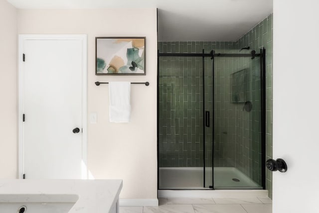 full bath featuring a shower stall, vanity, marble finish floor, and baseboards