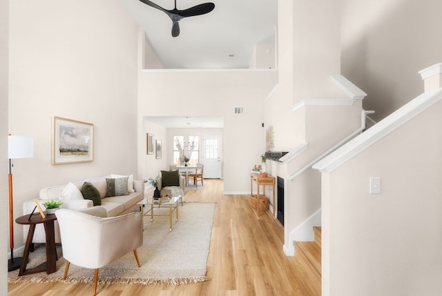 living room with stairway, a high ceiling, baseboards, and wood finished floors