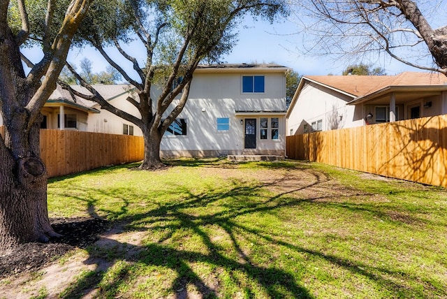 rear view of house featuring a lawn, entry steps, and a fenced backyard