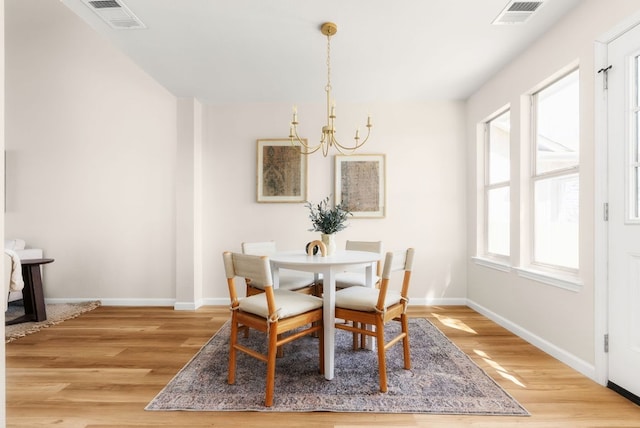 dining area with a notable chandelier, light wood-type flooring, and visible vents