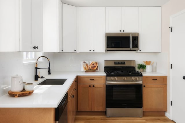 kitchen with a sink, white cabinets, and stainless steel appliances