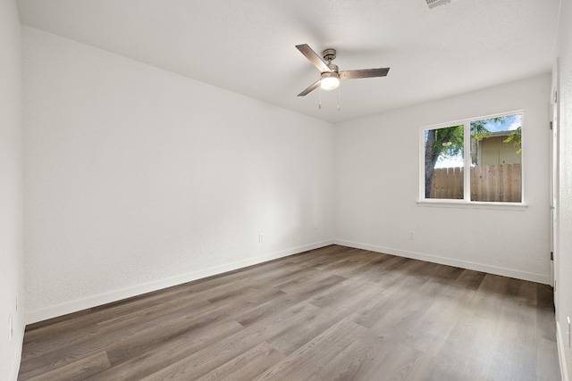 spare room with baseboards, ceiling fan, and wood finished floors