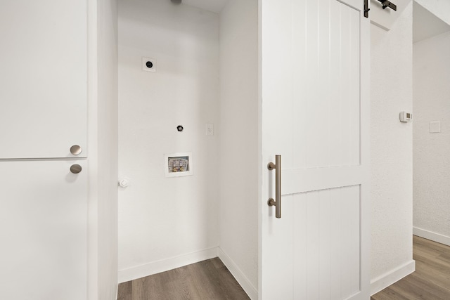 clothes washing area featuring a barn door, hookup for an electric dryer, dark wood finished floors, and laundry area