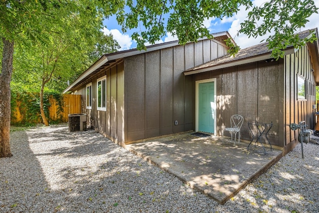 back of house with cooling unit, a patio, board and batten siding, and fence