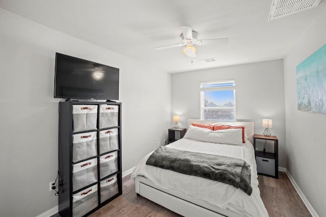 bedroom with ceiling fan, wood finished floors, visible vents, and baseboards