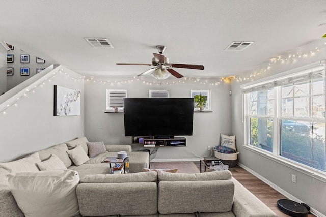 living room featuring visible vents, baseboards, wood finished floors, and a ceiling fan