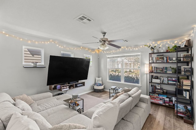 living area with visible vents, baseboards, wood finished floors, a textured ceiling, and a ceiling fan