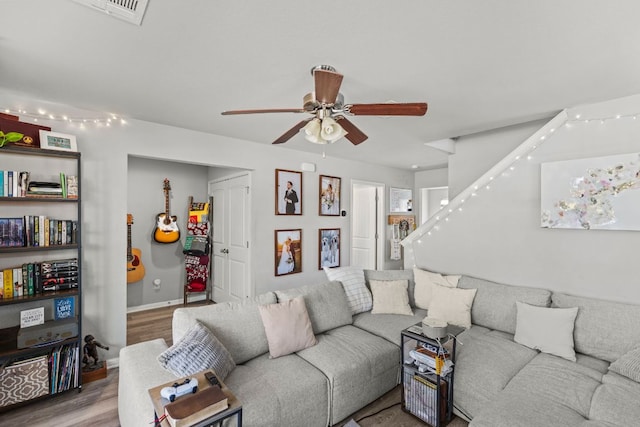 living area with visible vents, baseboards, stairs, wood finished floors, and a ceiling fan