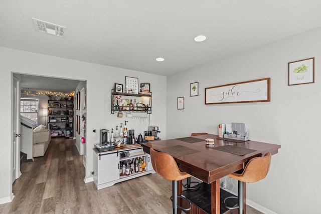 dining room with visible vents, wood finished floors, recessed lighting, a bar, and baseboards