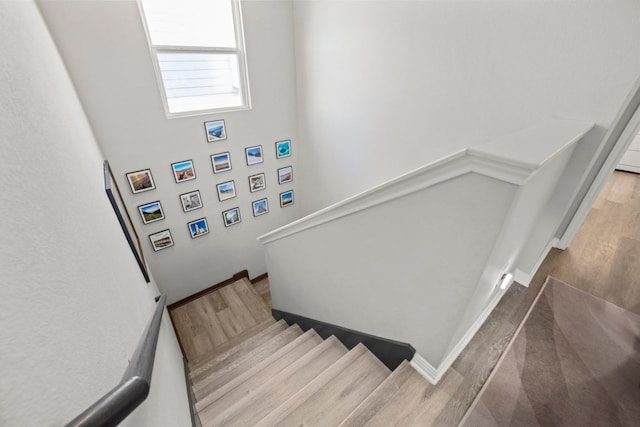 staircase featuring wood finished floors and baseboards