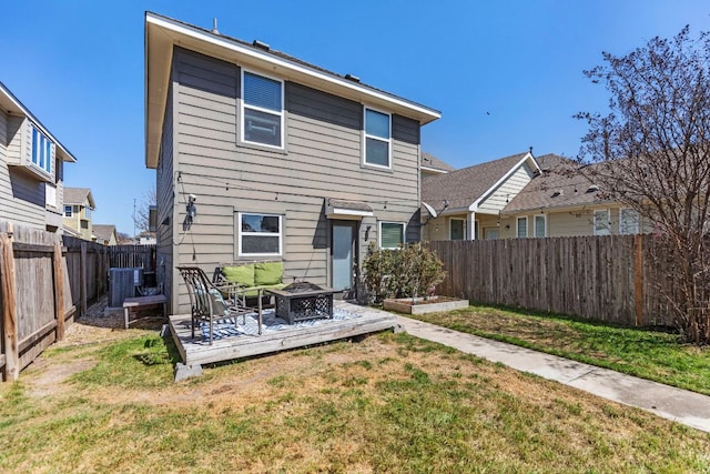 rear view of house featuring a yard, a fenced backyard, central AC, and an outdoor fire pit