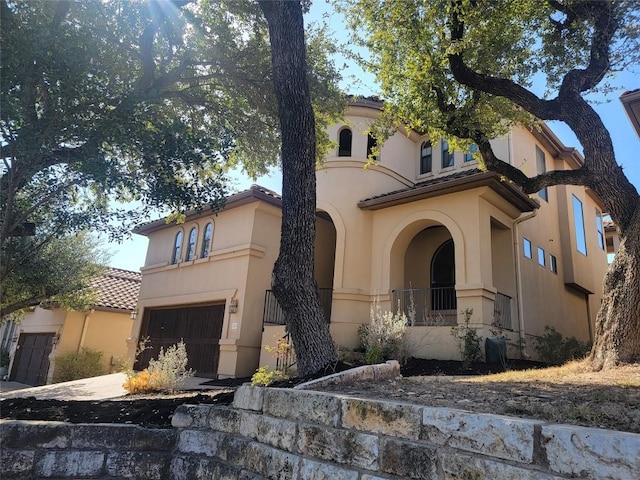 mediterranean / spanish house with stucco siding, concrete driveway, an attached garage, and a tiled roof