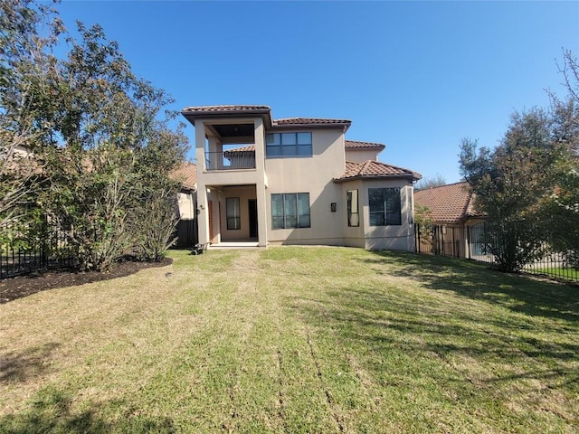 back of property featuring a yard, a tiled roof, a balcony, and fence