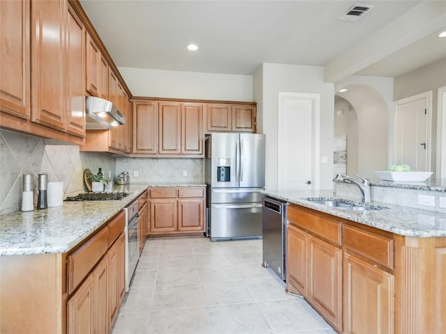 kitchen featuring visible vents, under cabinet range hood, a sink, arched walkways, and appliances with stainless steel finishes