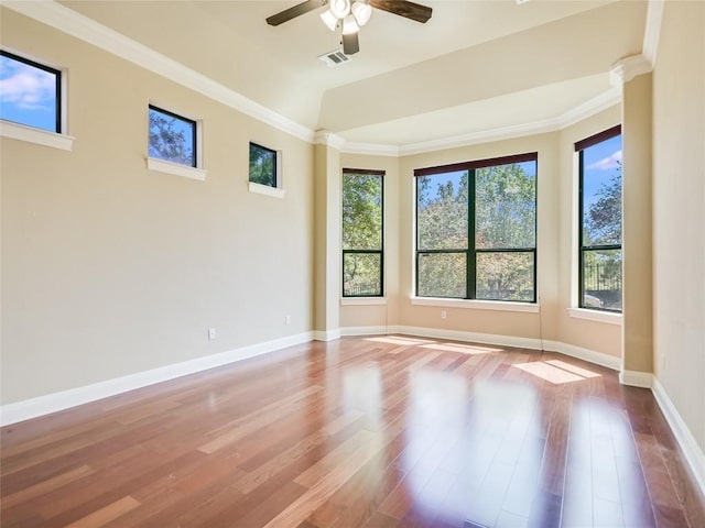 empty room featuring wood finished floors, a ceiling fan, baseboards, and a healthy amount of sunlight