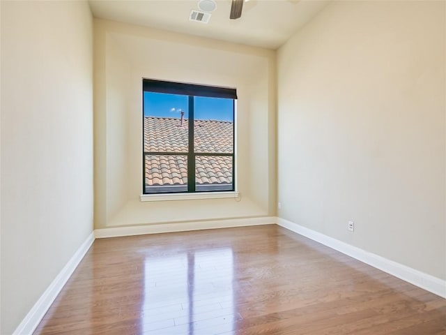 spare room featuring visible vents, wood finished floors, baseboards, and ceiling fan