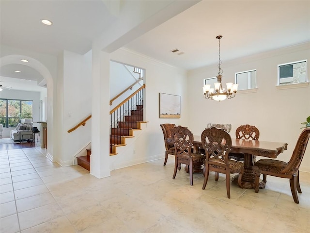 dining space featuring visible vents, crown molding, baseboards, a chandelier, and stairway