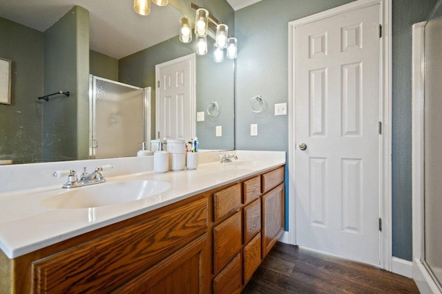 full bath featuring double vanity, a shower stall, wood finished floors, and a sink