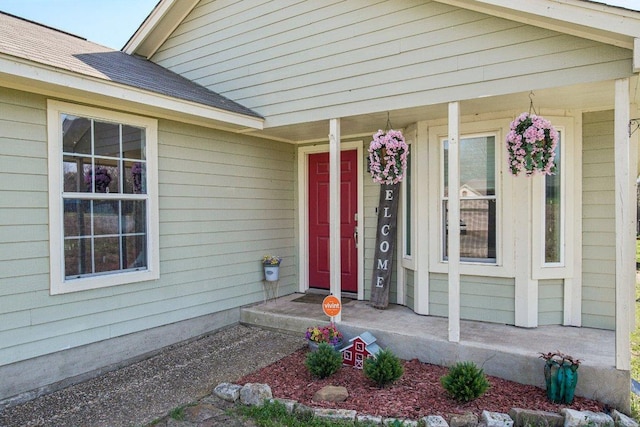 property entrance featuring covered porch and a shingled roof