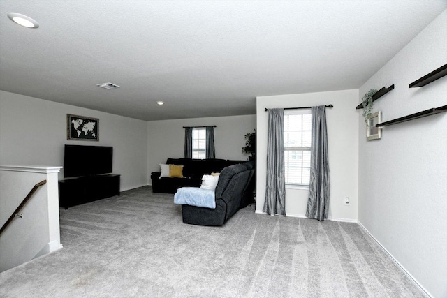 living area featuring carpet flooring, an upstairs landing, visible vents, and a textured ceiling