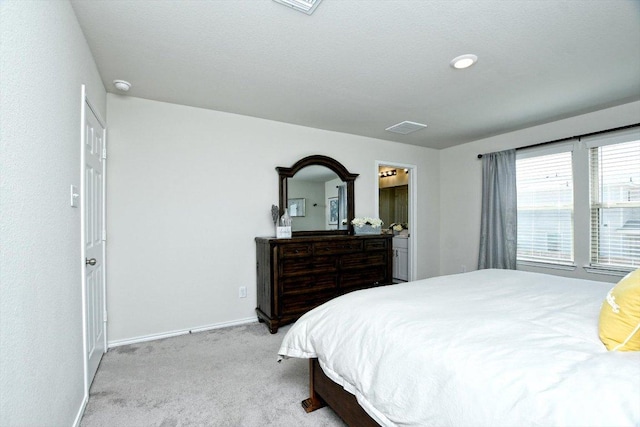 bedroom with visible vents, light colored carpet, connected bathroom, and baseboards