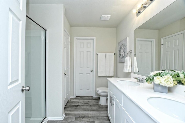 bathroom with toilet, a stall shower, wood finished floors, and a sink