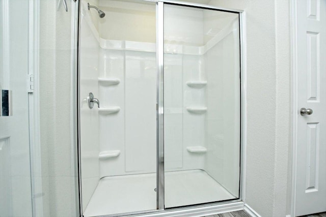 full bath featuring a shower stall and a textured wall