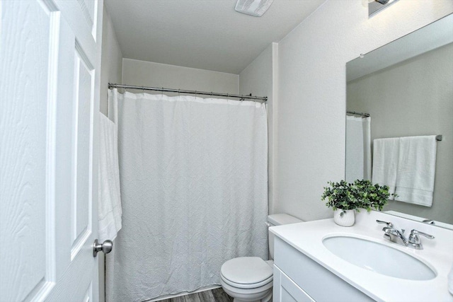 bathroom featuring toilet, wood finished floors, and vanity